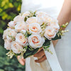 A bridal bouquet of pale pink and white silk roses held by a person.