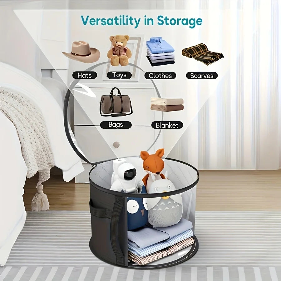 A black storage basket with a clear viewing window holds various items like hats, toys, clothes, scarves, bags, and a blanket