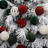 A close-up of a Christmas tree decorated with velvet hanging ornaments in shades of red, green, and white.