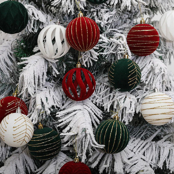 A close-up of a Christmas tree decorated with velvet hanging ornaments in shades of red, green, and white.