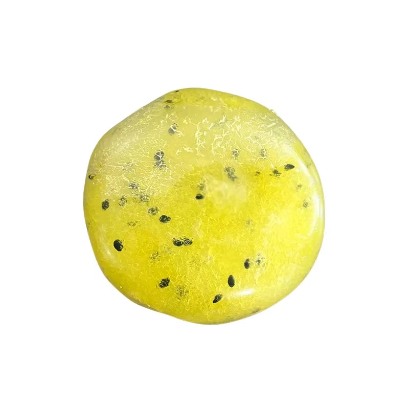 A bright yellow, spherical squishy toy filled with Vaseline, featuring small black specks.