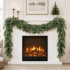 Artificial cedar garland draped over a white fireplace mantel with a roaring fire inside