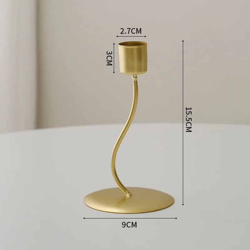 A gold-colored iron candle holder with a curved stem and a round base, shown against a light background.