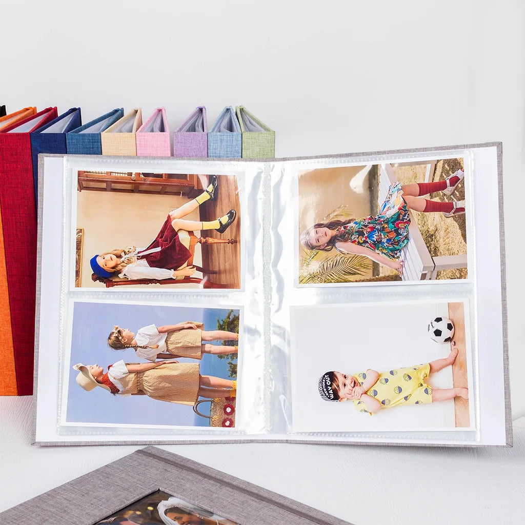An open linen photo album displaying four photos of children in various poses and outfits.