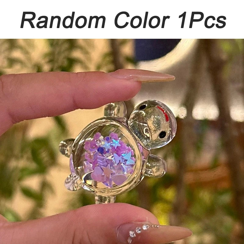 A hand holds a clear glow-in-the-dark mini sea turtle figurine with purple and blue glitter inside.