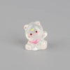 A small, translucent white resin figurine of a cat with pink accents and gold markings.