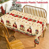 A vintage Christmas tablecloth featuring poinsettia and bell designs on a wooden table.