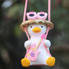 A cute pink anime duck ornament with pink goggles and a yellow beak, hanging by a pink string.