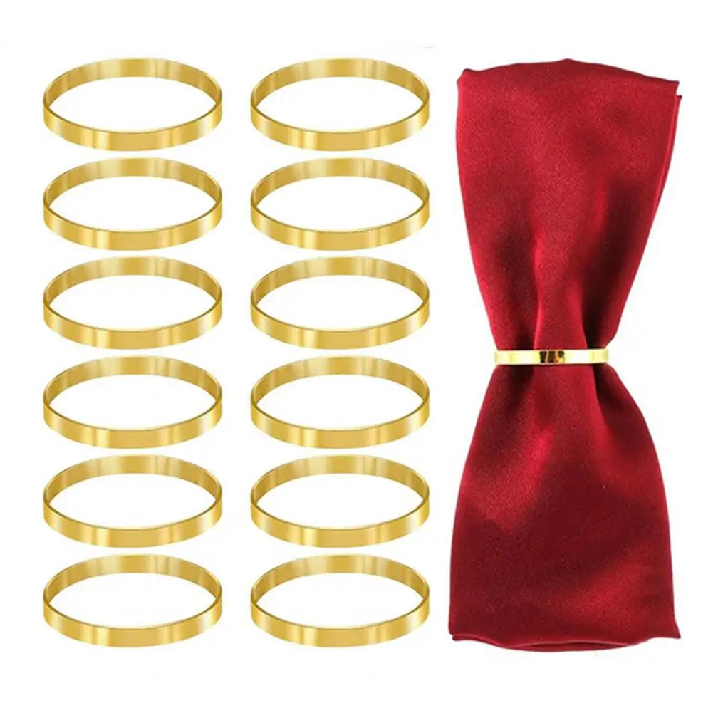 Ein Satz von zwölf eleganten goldenen Metallserviettenringen neben einem gefalteten dunkelroten Seidenserviette.
