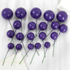 A set of twenty deep purple spherical ball cake toppers on thin green stems.