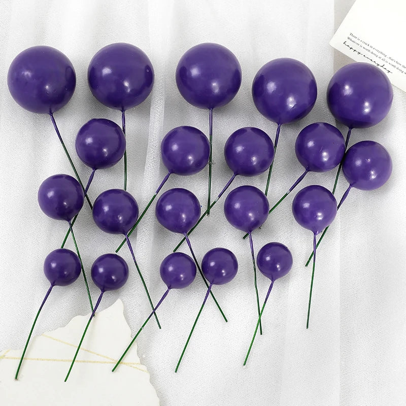 A set of twenty deep purple spherical ball cake toppers on thin green stems.