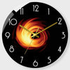 A black round clock face with a fiery orange sunburst design and gold hands.