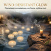 Water-resistant floating LED candles glowing in calm water surrounded by rocks and mist