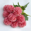 A cluster of pink artificial hydrangea and camellia flowers with green leaves.