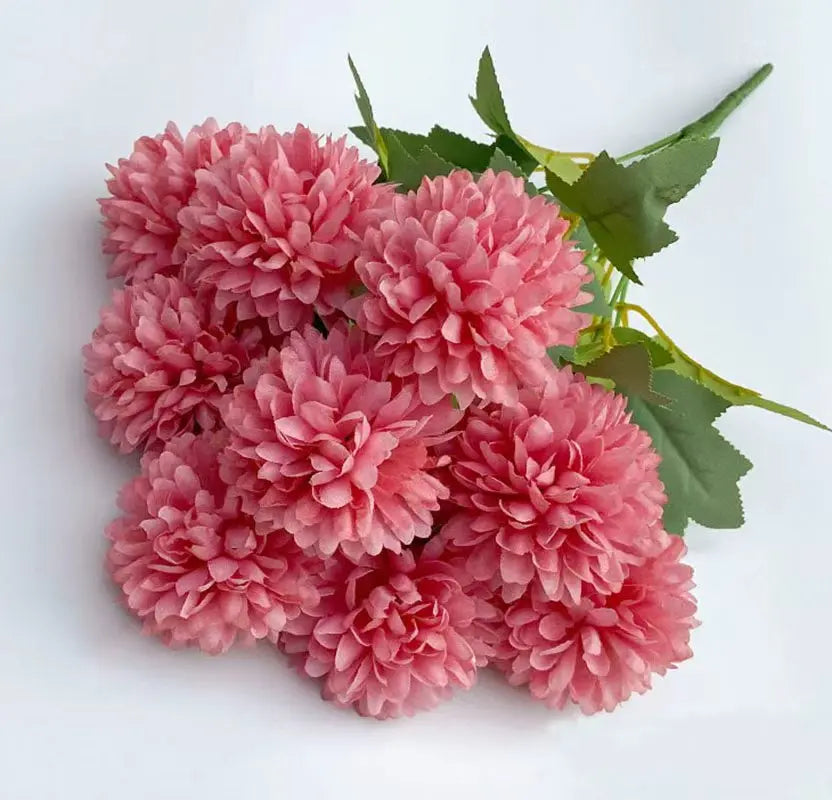 A cluster of pink artificial hydrangea and camellia flowers with green leaves.