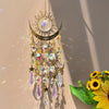 A hanging gold star moon wind chime decoration with clear crystals and gold accents, illuminated by sunlight.
