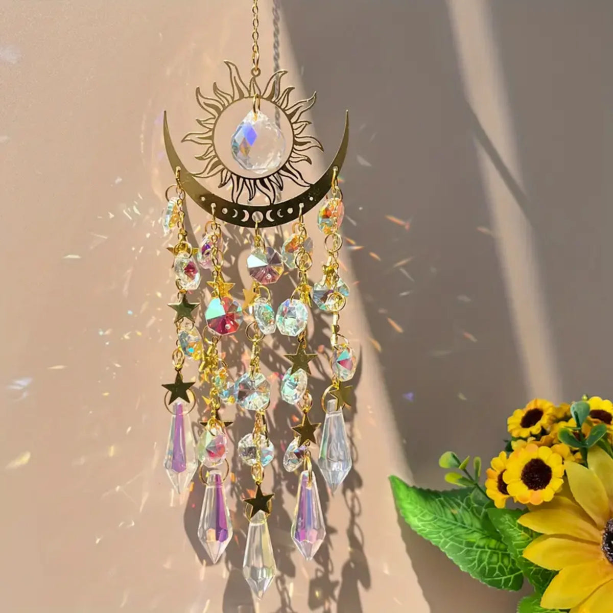 A hanging gold star moon wind chime decoration with clear crystals and gold accents, illuminated by sunlight.