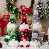 Three festive knitted gnome decorations with white beards and red accents displayed on a white surface.