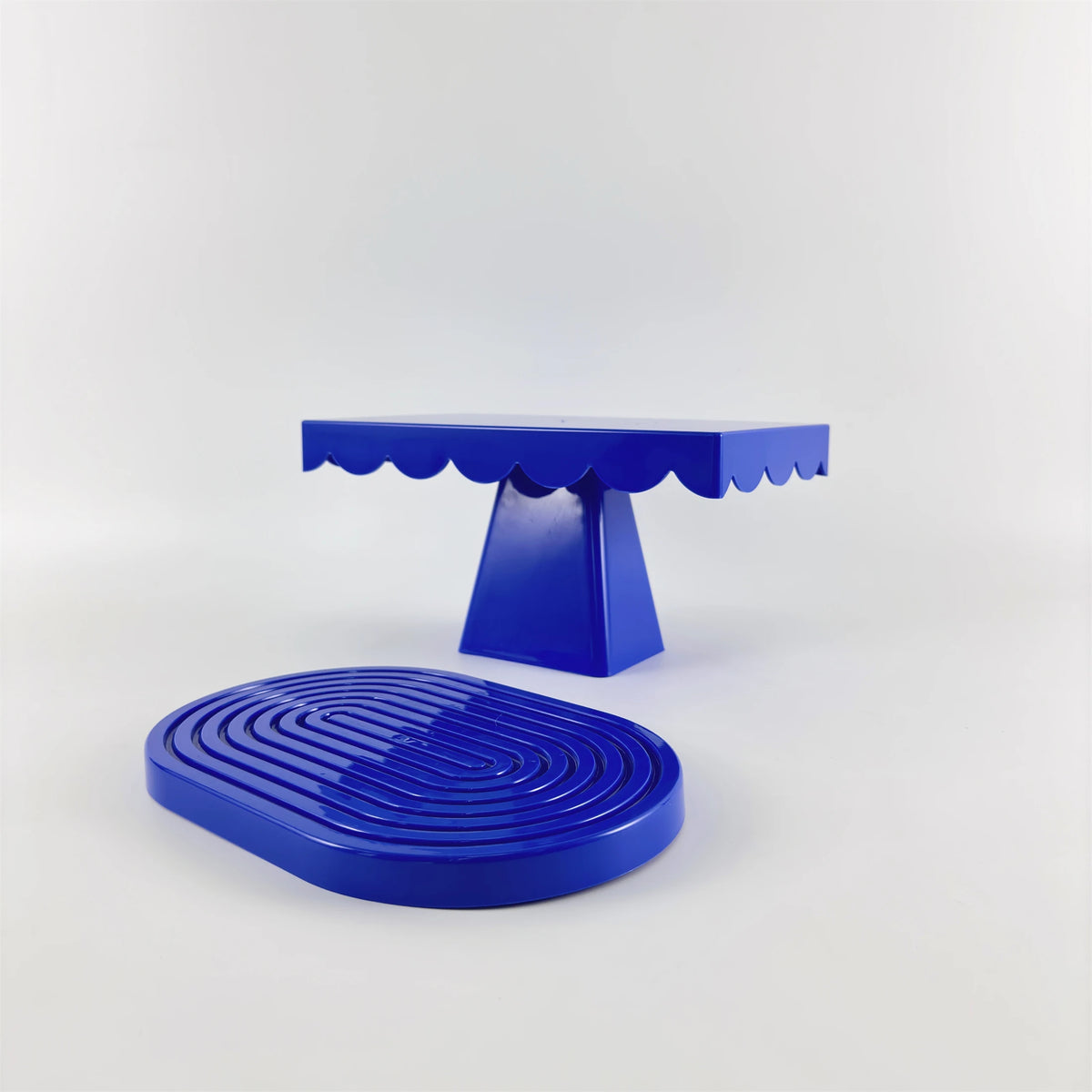 A set of two bright blue cupcake stands with decorative scalloped edges.