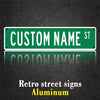 A green aluminum street sign with the text CUSTOM NAME ST mounted on a dark surface.