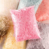 A pile of vibrant pink crinkle paper shreds next to yellow and gray shredded paper products.