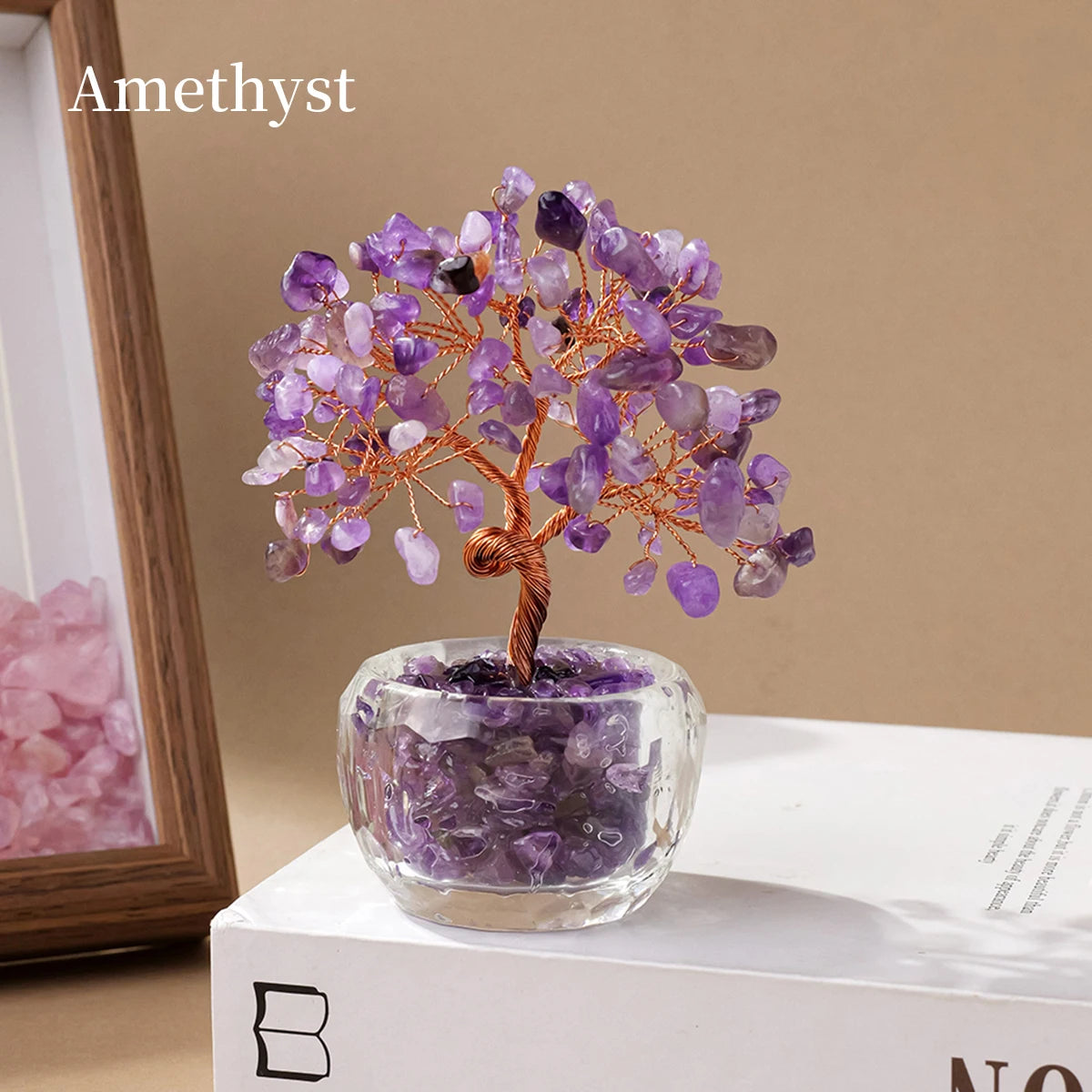 A crystal money tree ornament featuring purple amethyst clusters on a wooden branch displayed in a glass pot.
