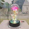 An eternal rose in a glass dome illuminated by an LED light, displayed on a black base.