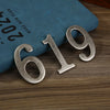 Magnetic silver house number 619 displayed on a dark blue book.
