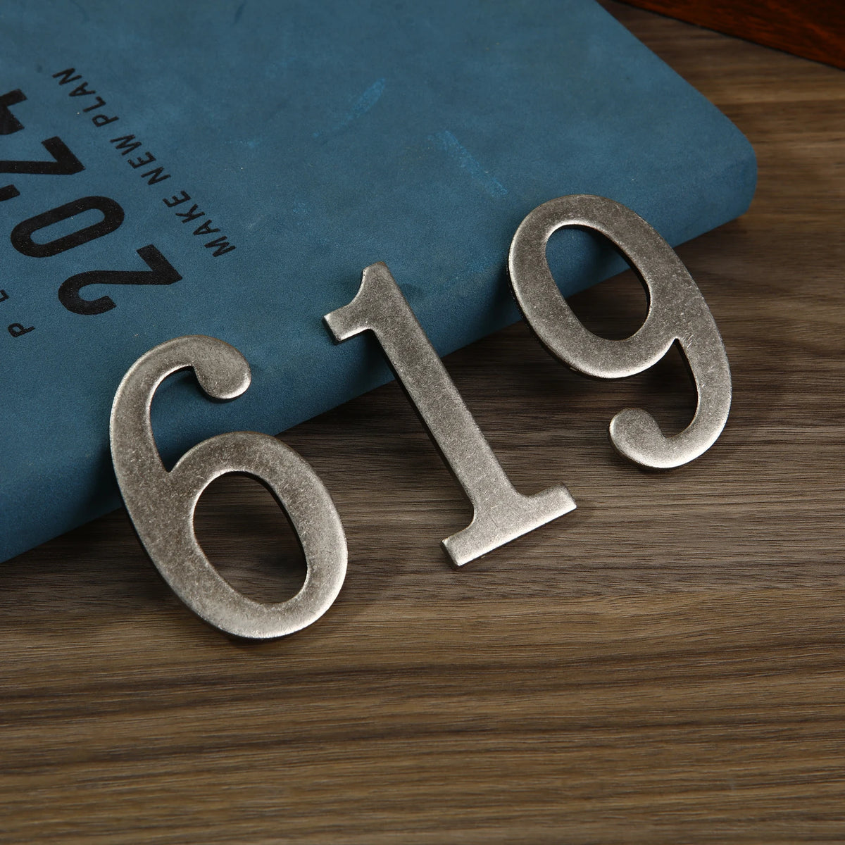 Magnetic silver house number 619 displayed on a dark blue book.
