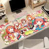 A desk mat featuring five female anime characters from The Quintessential Quintuplets series with a floral pattern.
