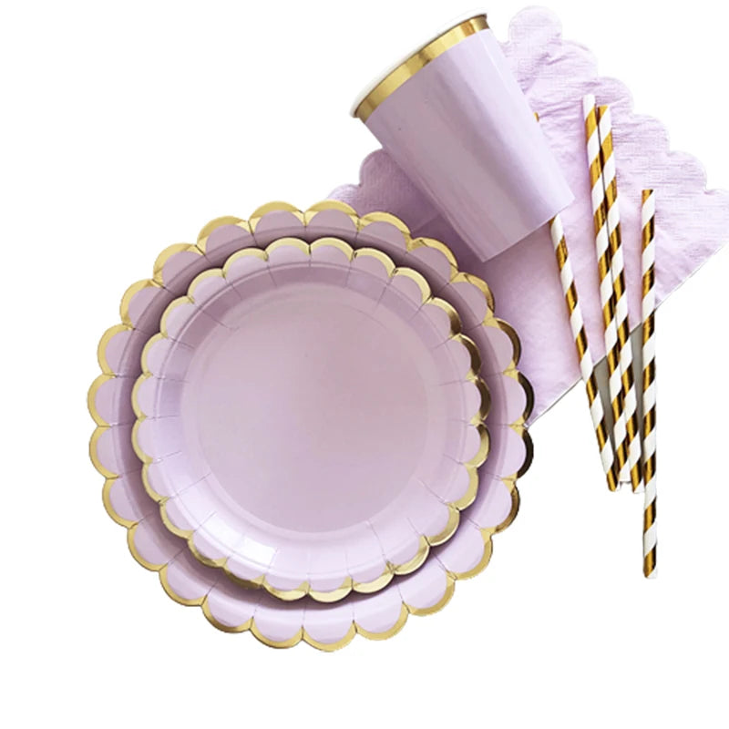 A purple and gold party tableware set featuring a plate and a cup, set on a pink napkin.