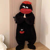 A black coral fleece hooded sleepsuit resembling a monster with red features hanging on a door.