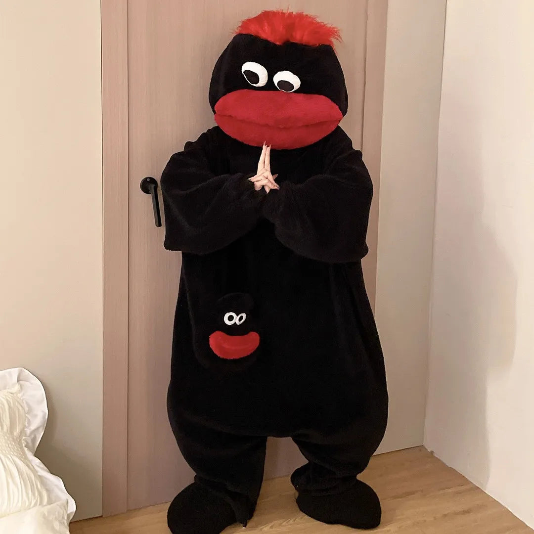 A black coral fleece hooded sleepsuit resembling a monster with red features hanging on a door.