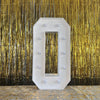 A large, white marquee light-up letter in the shape of the number '0' mounted against a shimmering gold curtain backdrop.