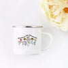 A white enamel mug featuring a line drawing of various flowers and the text teach them love them watch them grow.