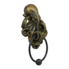 A bronze-colored octopus skull door knocker with a cast iron ring.
