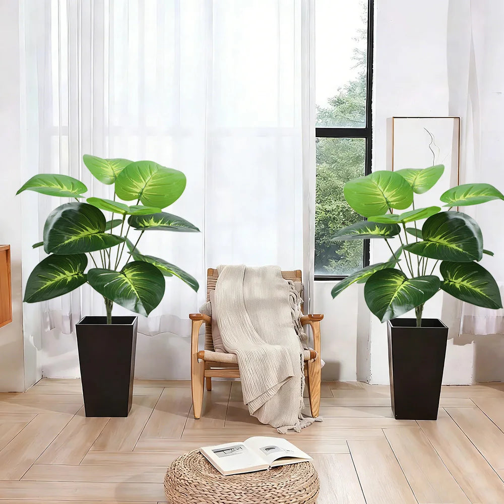 A potted artificial palm tree with large green leaves sits on a wooden floor next to a window.