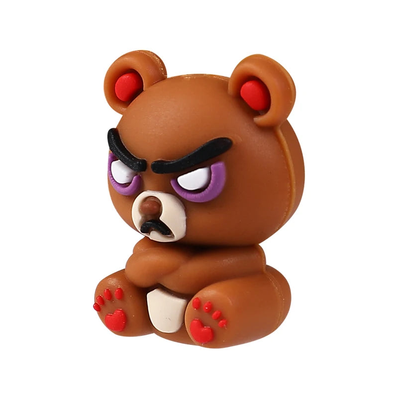 A small, brown silicone bear figurine with purple eyes and red accents.