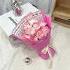 A bouquet of pink artificial roses wrapped in pink paper and tied with a ribbon sits next to a book titled Minimalist.