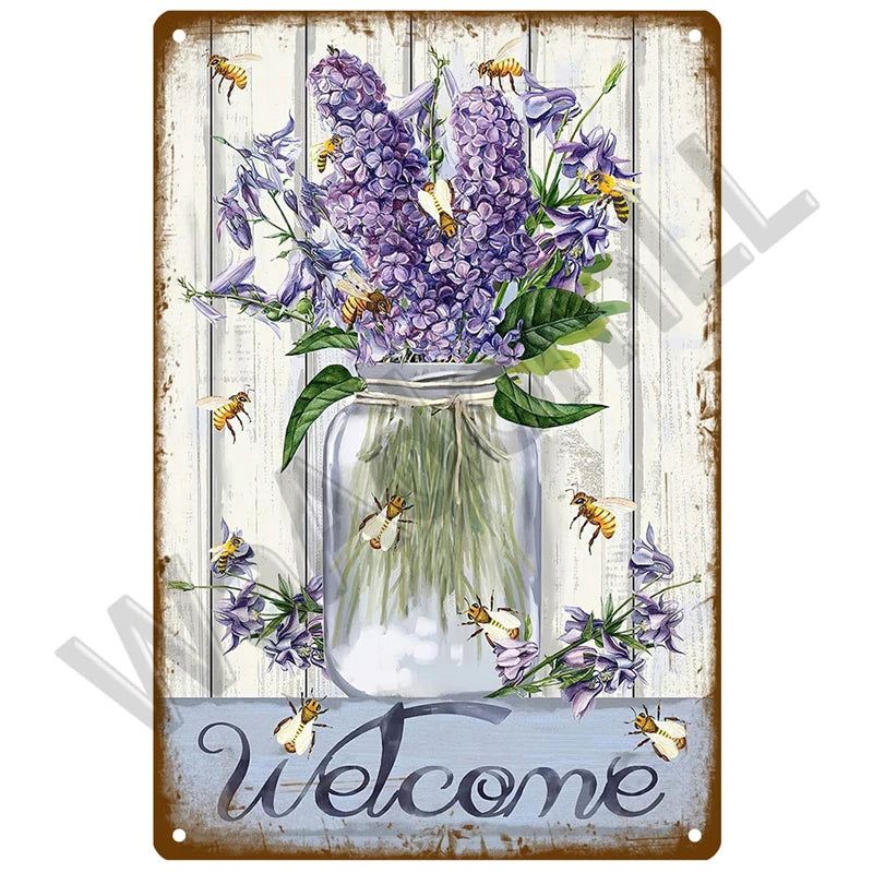 A vintage metal sign featuring a glass jar filled with purple lavender flowers and several bees, with the word welcome writte