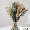 A bouquet of natural dried flowers featuring various textures and shades of beige, green, and purple eucalyptus.