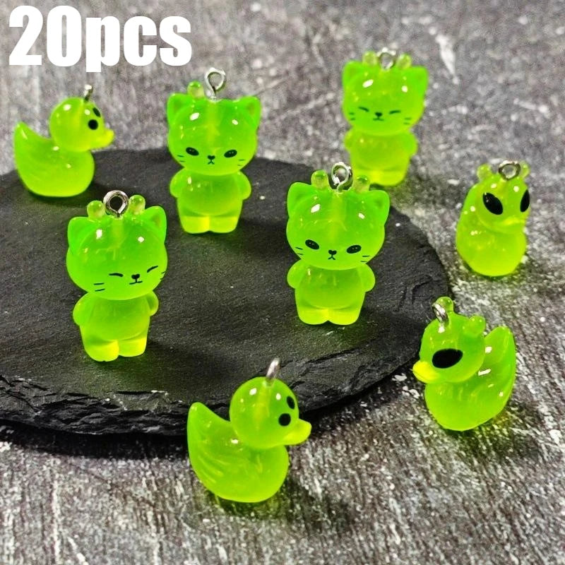 20 pieces of glow-in-the-dark green cartoon alien kitty duck resin charms displayed on a dark surface.