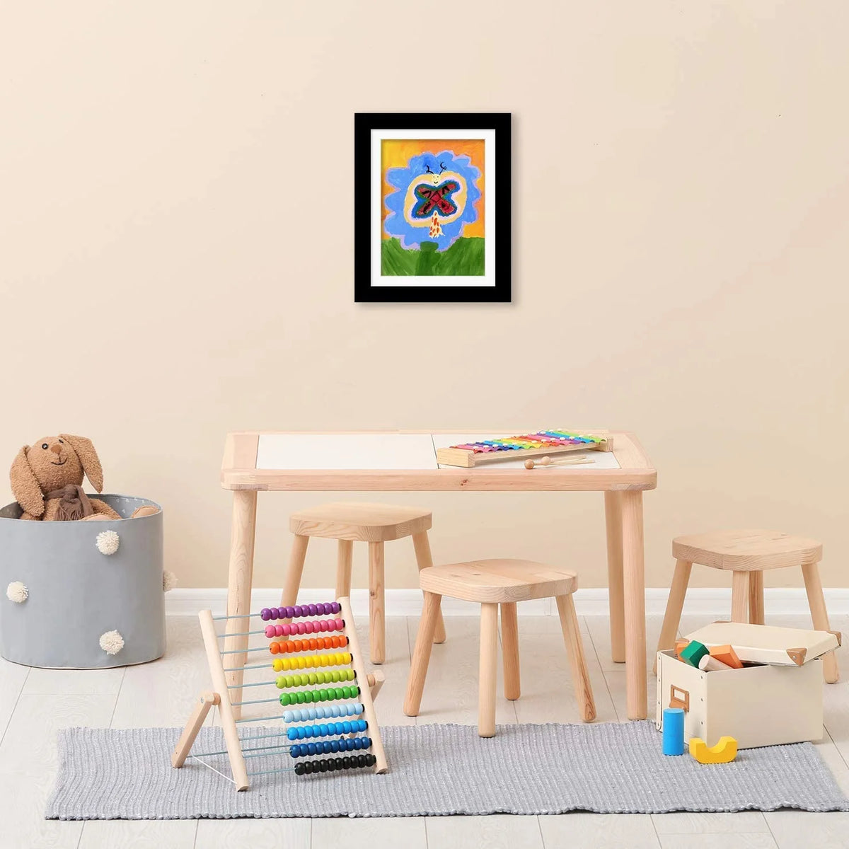A framed artwork featuring a red and black butterfly on a blue background, displayed on a wooden table.