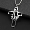Silver hollow prayer hands cross pendant hanging from a chain on a black background