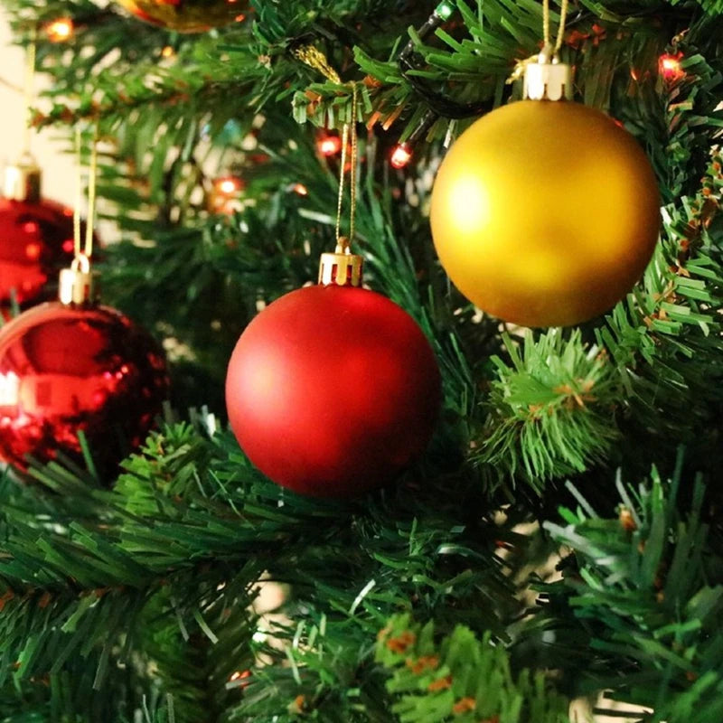 Two shiny round ornaments, one gold and one red, hanging on a green Christmas tree.