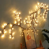 Willow branch string lights illuminate a wall, featuring delicate glowing lights on thin branches.