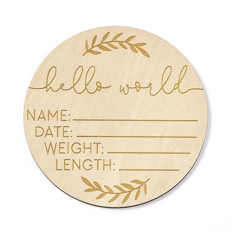 A round natural wood baby milestone disc with handwritten lines for name date weight and length measurements.