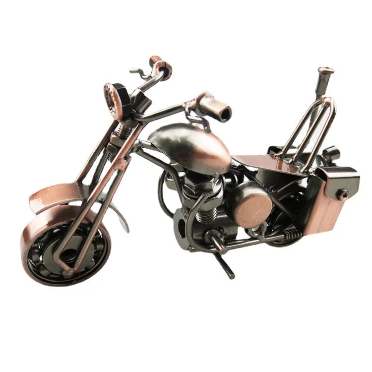 A vintage iron motorcycle figurine with a patina finish, displayed on a desk.