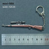 A miniature metallic gun model keychain with a silver-colored finish and a metal ring attached.