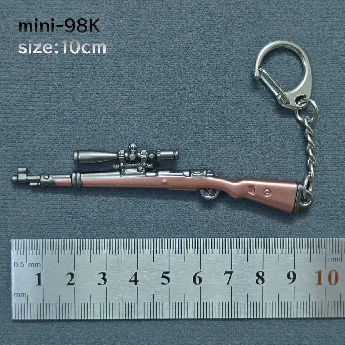 A miniature metallic gun model keychain with a silver-colored finish and a metal ring attached.